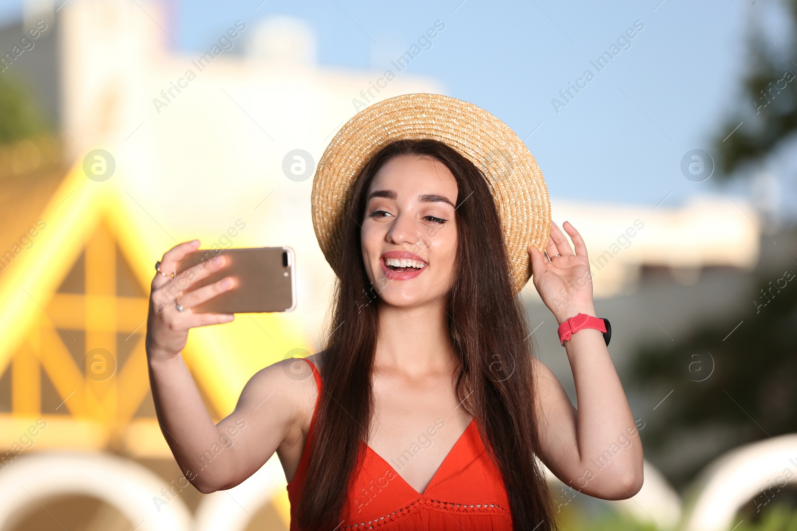 Photo of Happy young woman taking selfie outdoors on sunny day