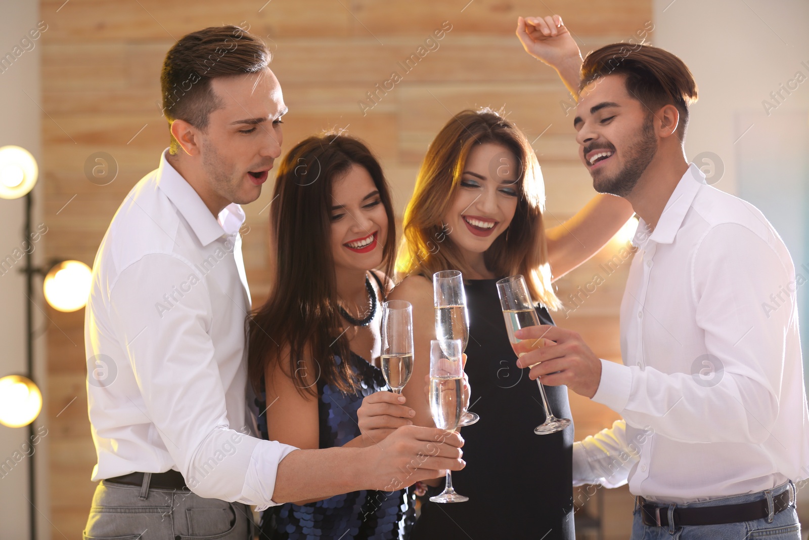 Photo of Friends clinking glasses with champagne at party indoors