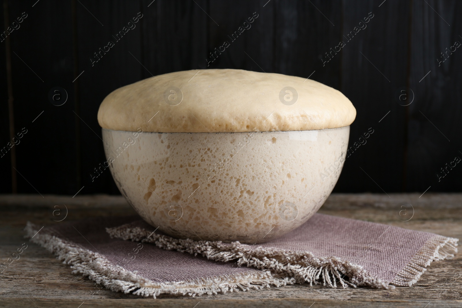 Photo of Bowl of fresh yeast dough on wooden table