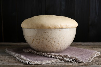 Photo of Bowl of fresh yeast dough on wooden table