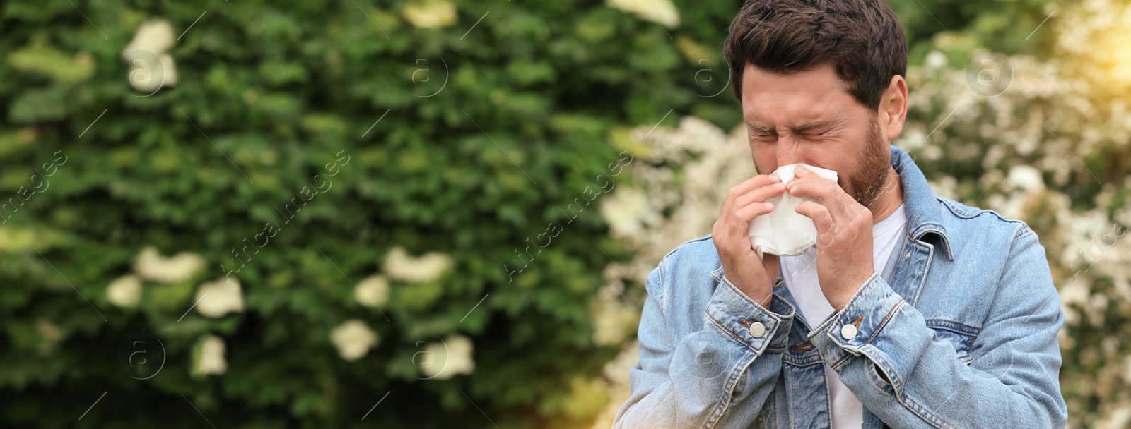 Image of Man suffering from seasonal pollen allergy on spring day. Banner design with space for text