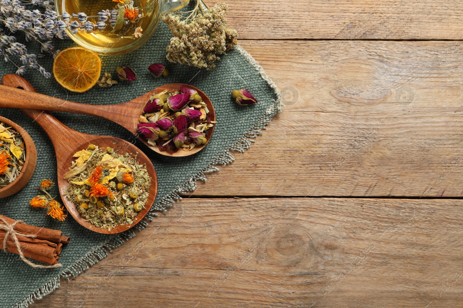 Photo of Mix of dried herbs and tea on wooden table, flat lay. Space for text