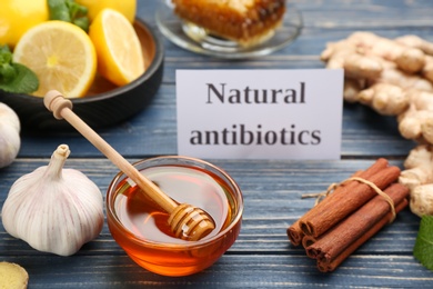 Photo of Different fresh products and card with phrase Natural Antibiotic on blue wooden table