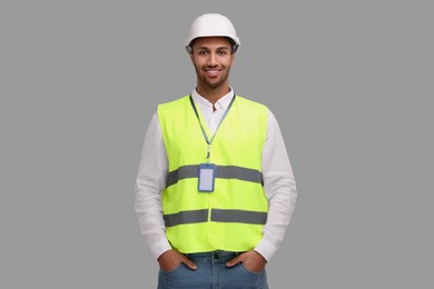 Engineer with hard hat and badge on grey background