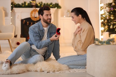 Photo of Man with engagement ring making proposal to his girlfriend at home on Christmas