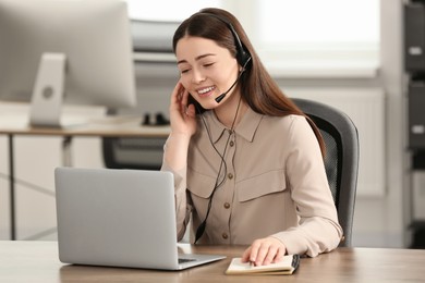 Hotline operator with headset working on laptop in office
