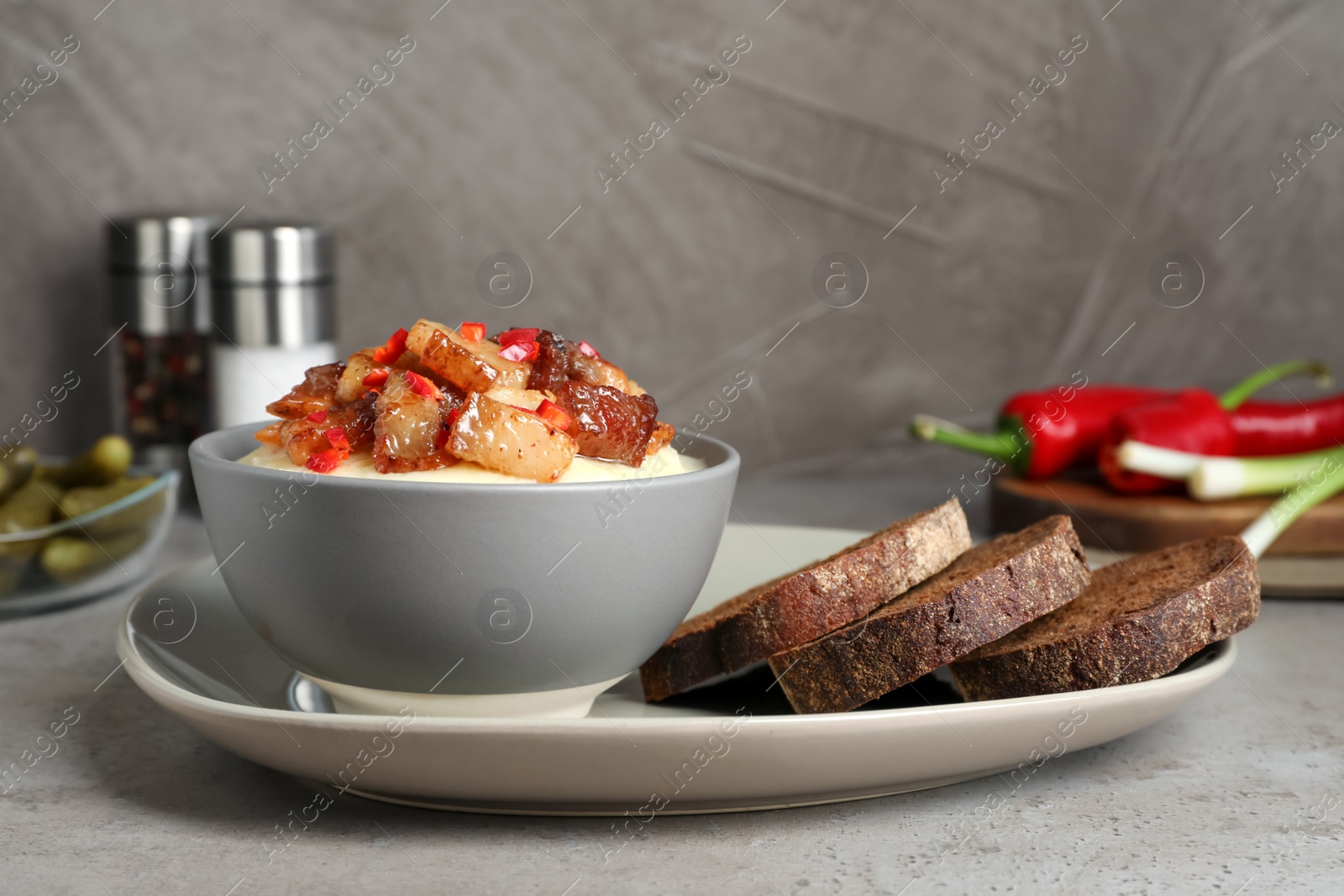 Photo of Potato puree and tasty fried cracklings on grey table. Cooked pork lard