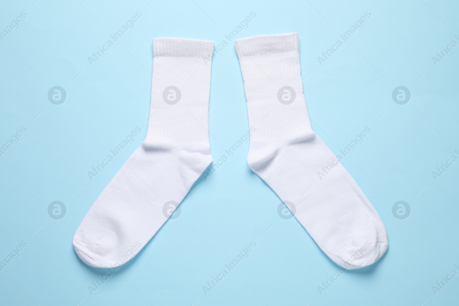 Photo of Pair of white socks on light blue background, flat lay