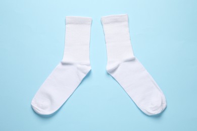 Pair of white socks on light blue background, flat lay