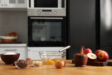 Cooking process. Metal whisk, bowl and products on wooden table in kitchen