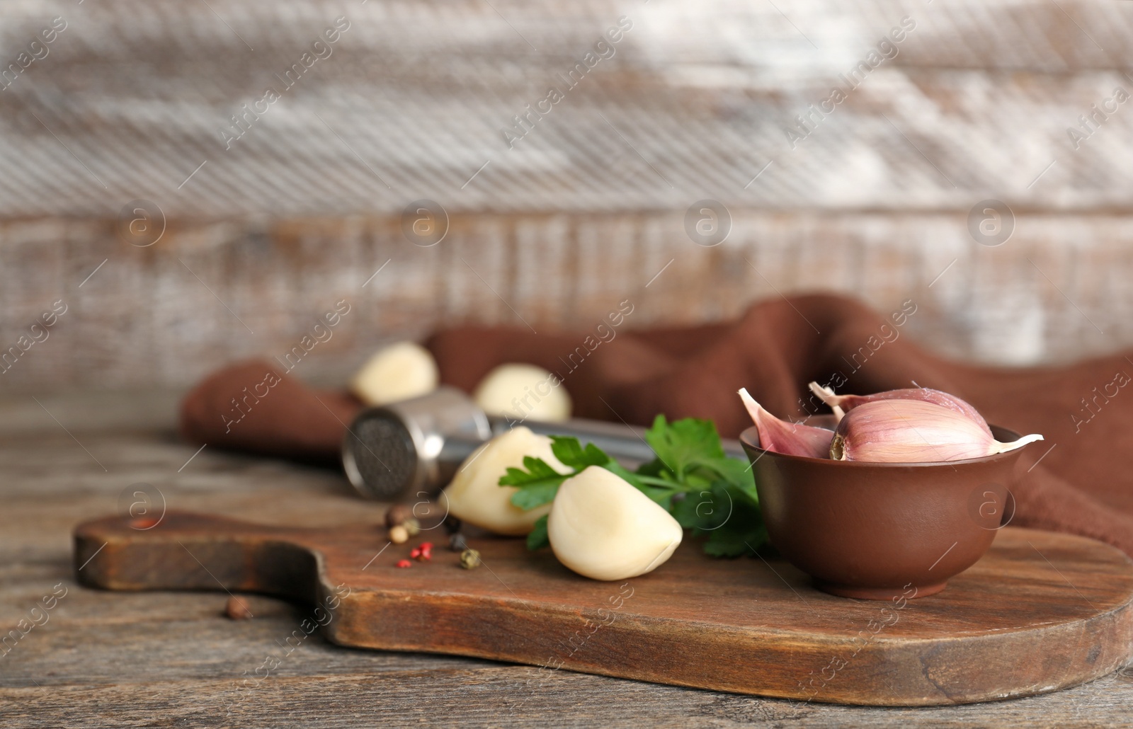 Photo of Garlic press and cloves on wooden board. Kitchen utensil