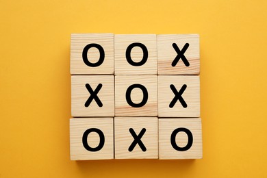 Tic tac toe cube set on yellow background, flat lay