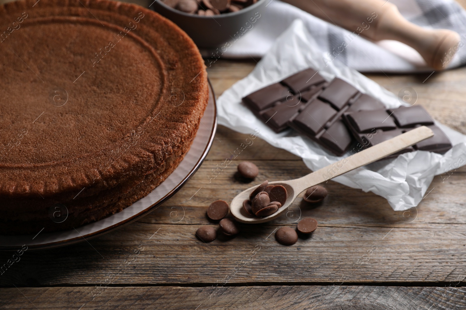 Photo of Delicious homemade sponge cake and different kinds of chocolate on wooden table, closeup