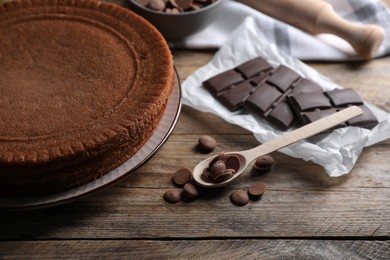 Delicious homemade sponge cake and different kinds of chocolate on wooden table, closeup