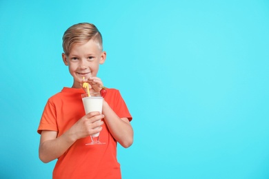 Photo of Little boy with glass of milk shake on color background