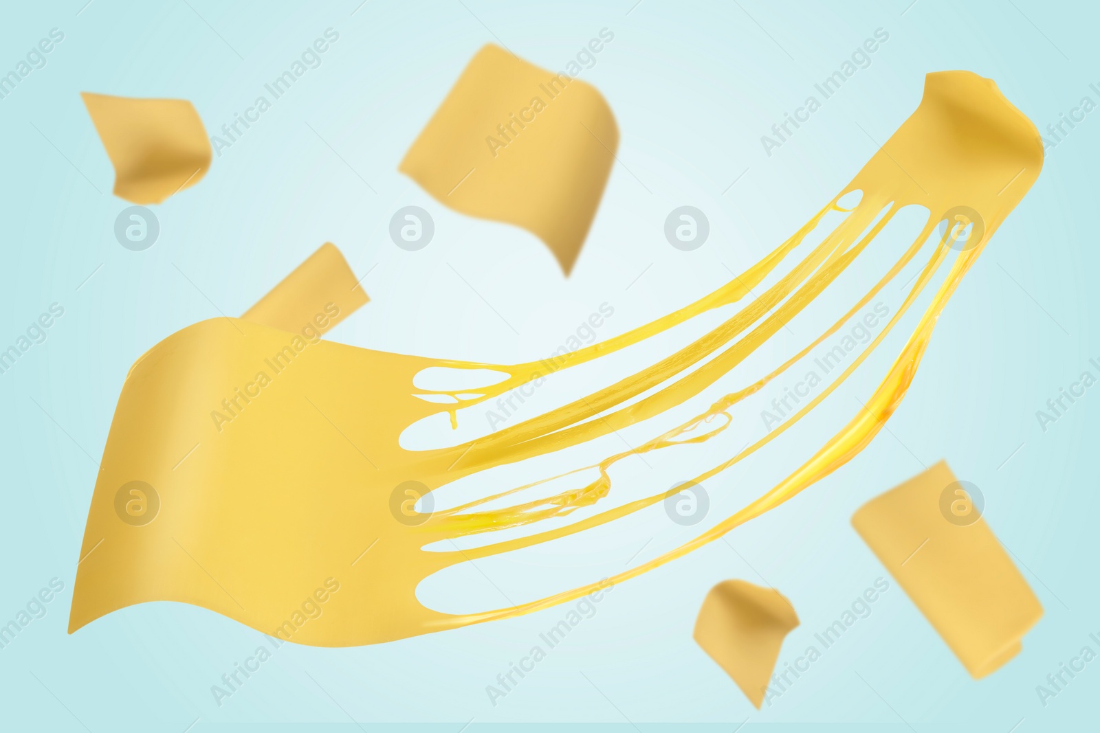 Image of Slices of cheese falling on light blue background