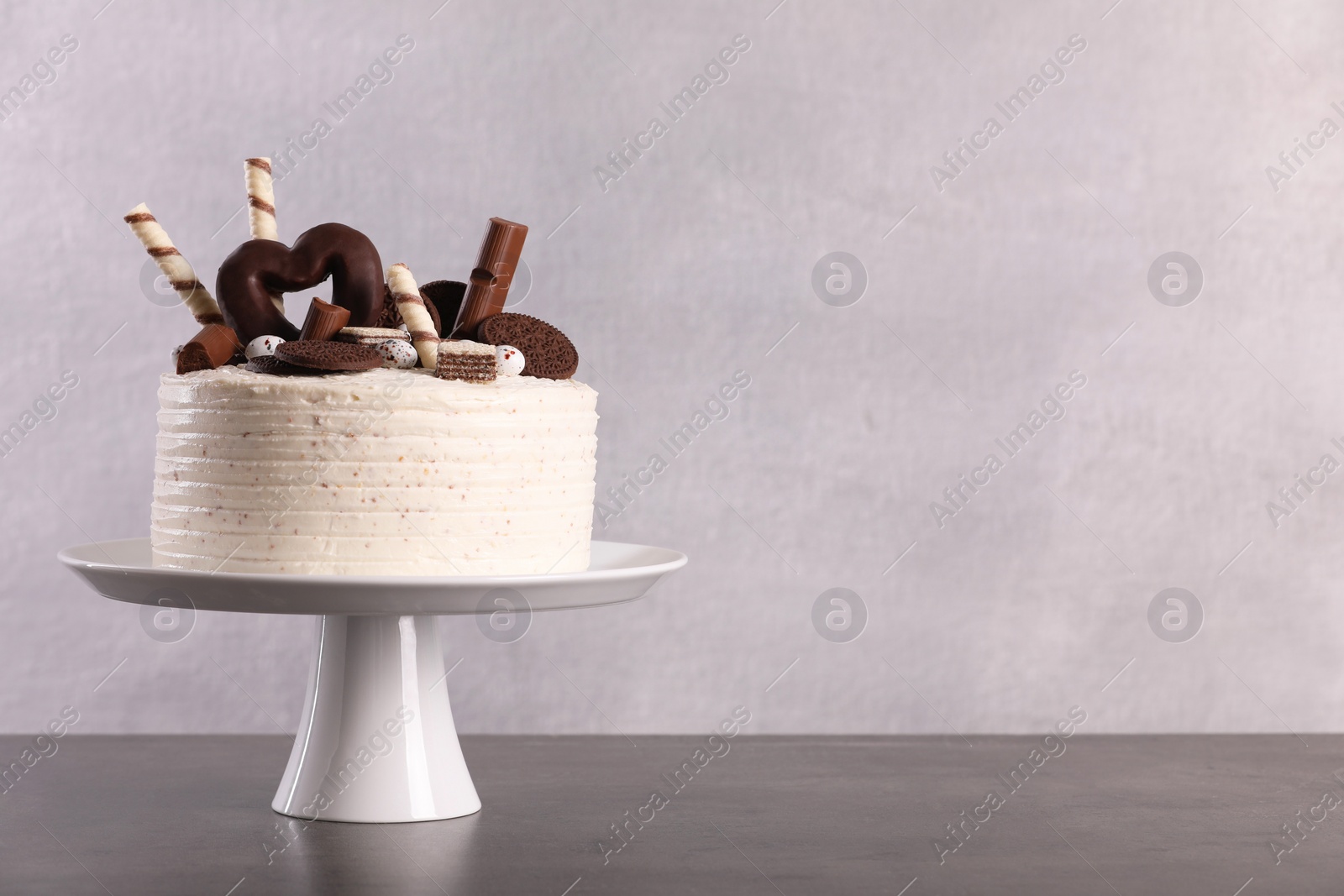 Photo of Delicious cake decorated with sweets on grey table, space for text