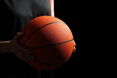 Photo of Basketball player with ball on black background, closeup. Space for text