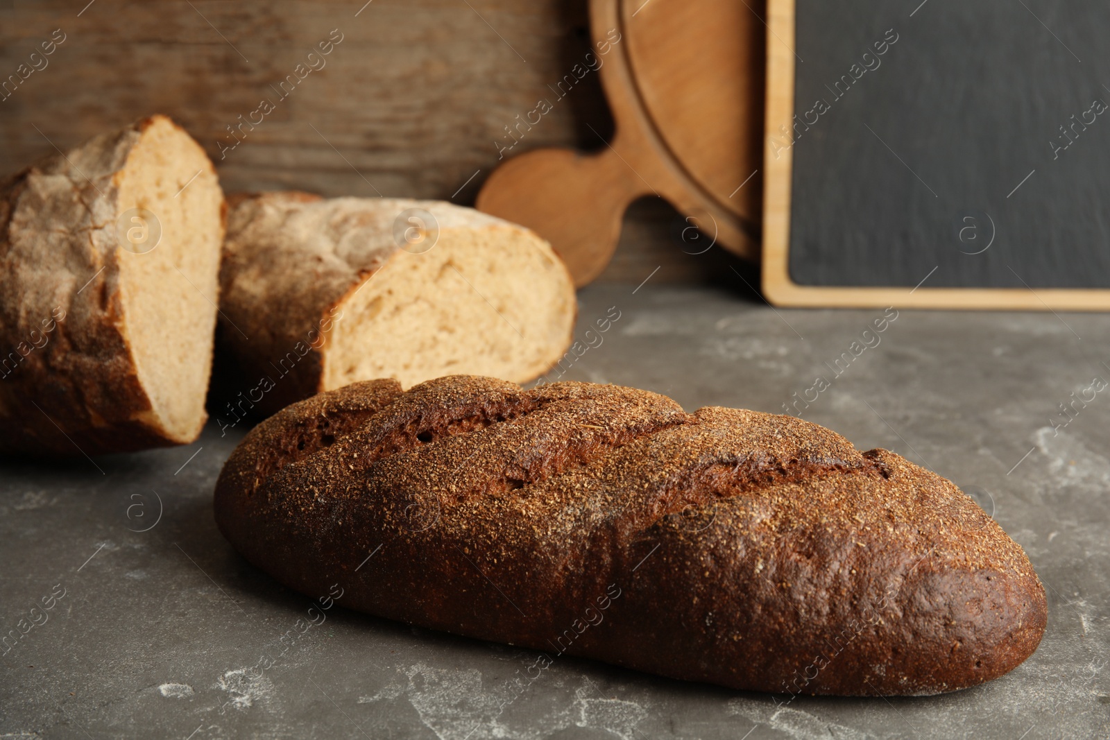 Photo of Loaf of fresh rye bread on grey table