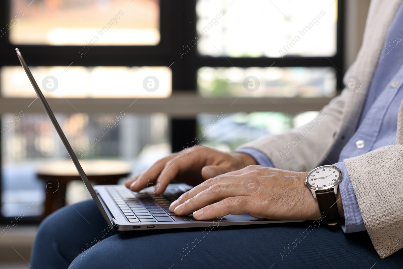 Photo of Man using modern laptop in cafe, closeup