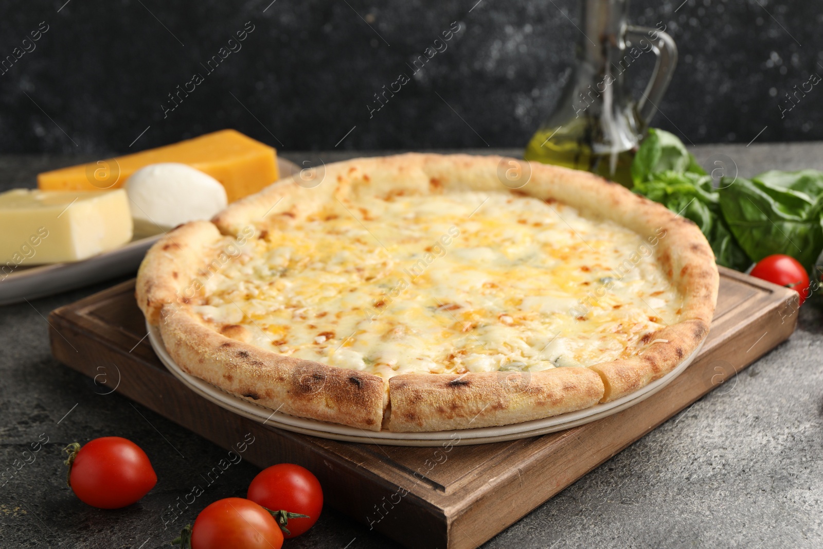 Photo of Delicious cheese pizza and ingredients on dark grey table