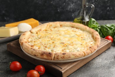 Photo of Delicious cheese pizza and ingredients on dark grey table