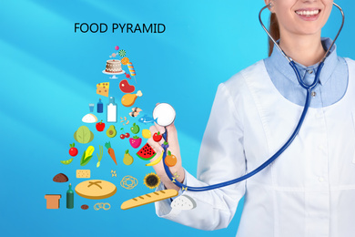 Image of Nutritionist and food pyramid on light blue background, closeup