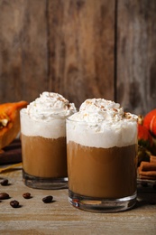 Photo of Glasses with tasty pumpkin spice latte on wooden table