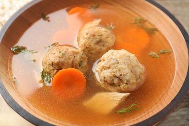 Photo of Bowl of Jewish matzoh balls soup on table, closeup