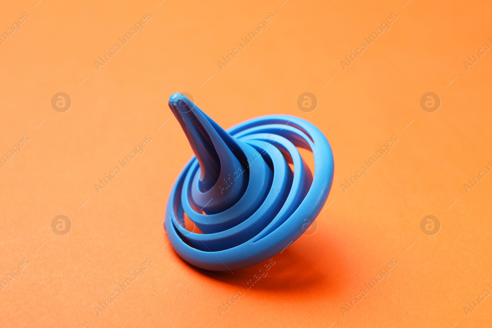 Photo of One blue spinning top on orange background, closeup