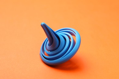 Photo of One blue spinning top on orange background, closeup