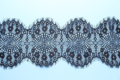 Photo of Black lace on light blue background, top view