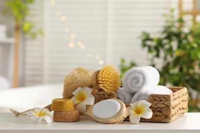 Photo of Composition with different spa products and plumeria flowers on white table in bathroom