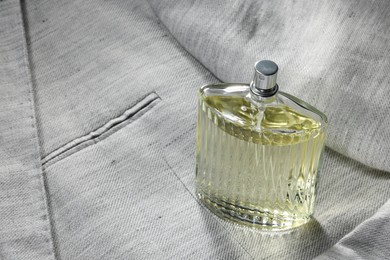 Luxury men's perfume in bottle on grey jacket, space for text