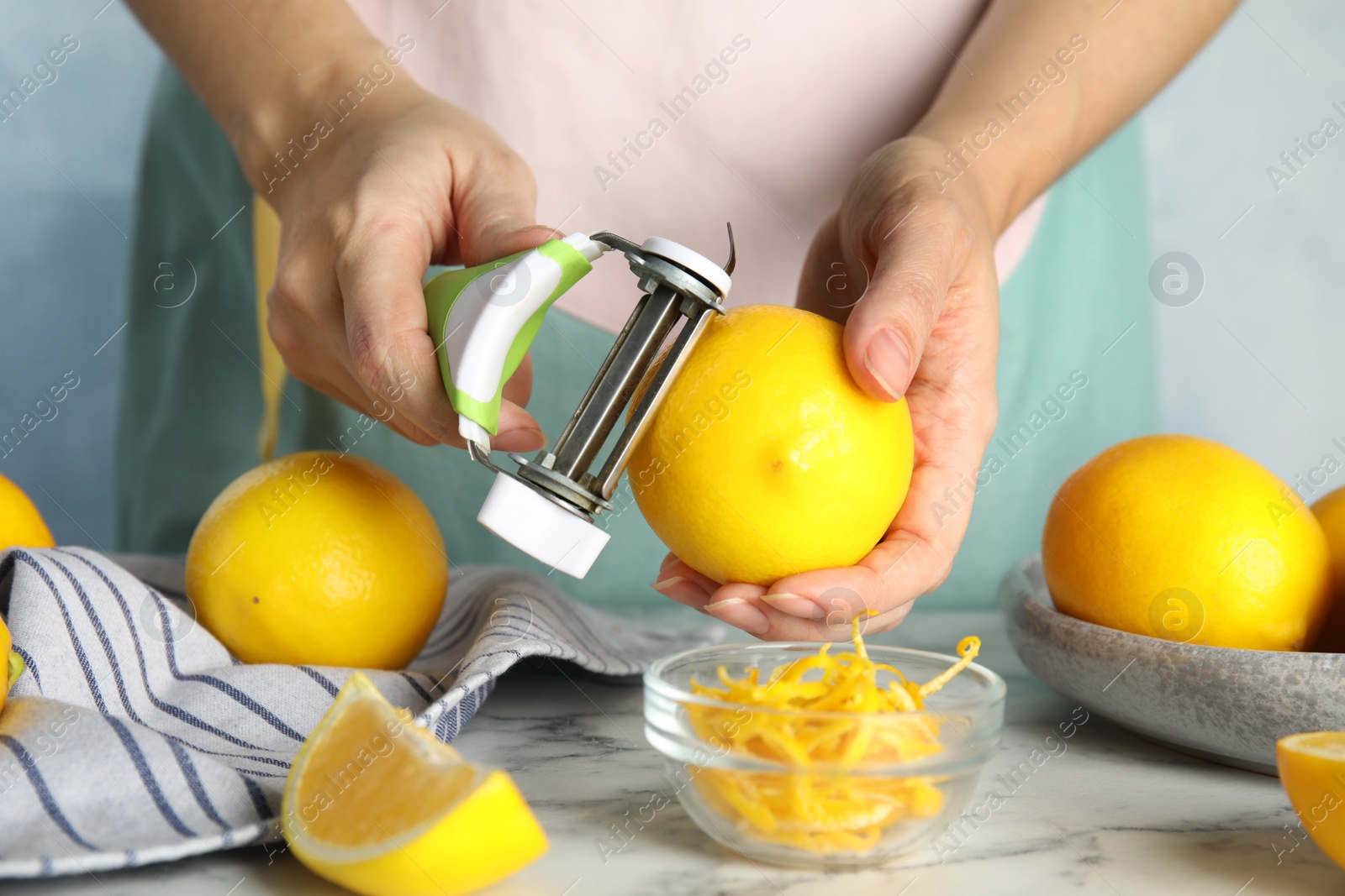 Photo of Woman zesting lemon at white marble table, closeup