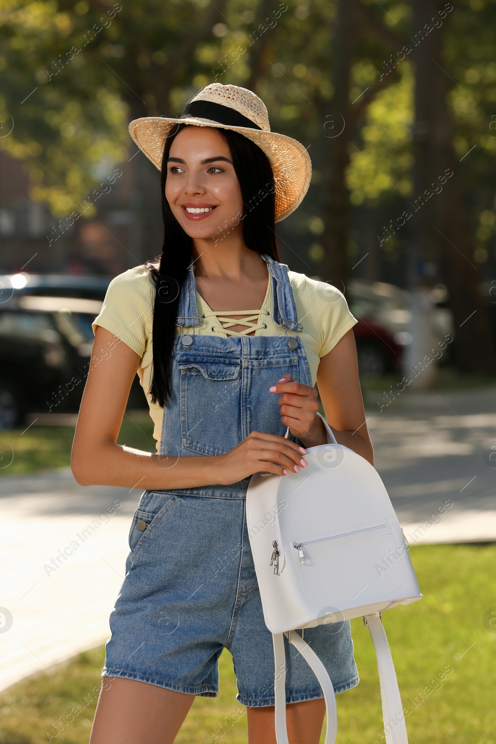 Photo of Beautiful young woman with stylish white backpack on city street