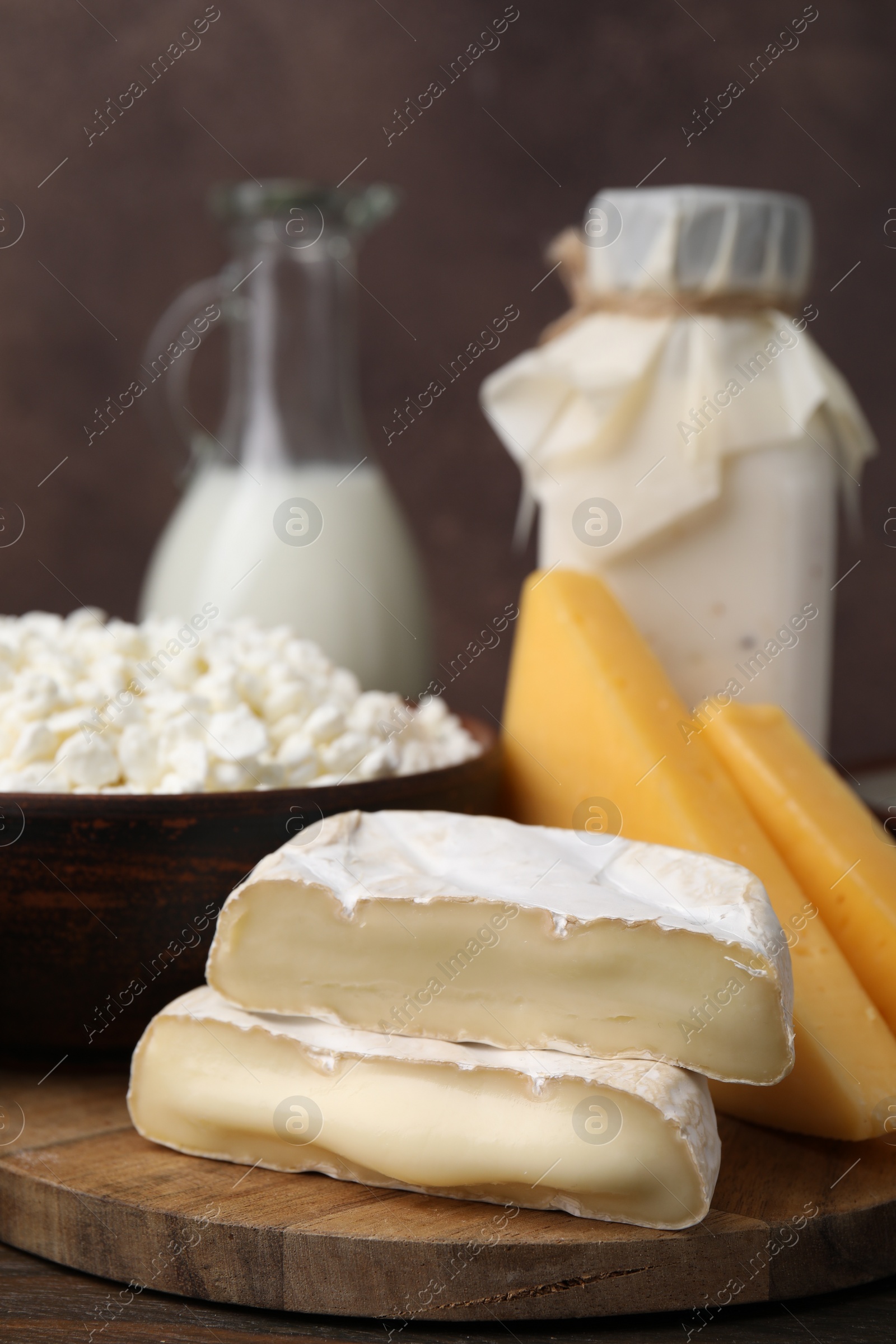 Photo of Dairy products. Milk and different kinds of cheese on wooden table, closeup