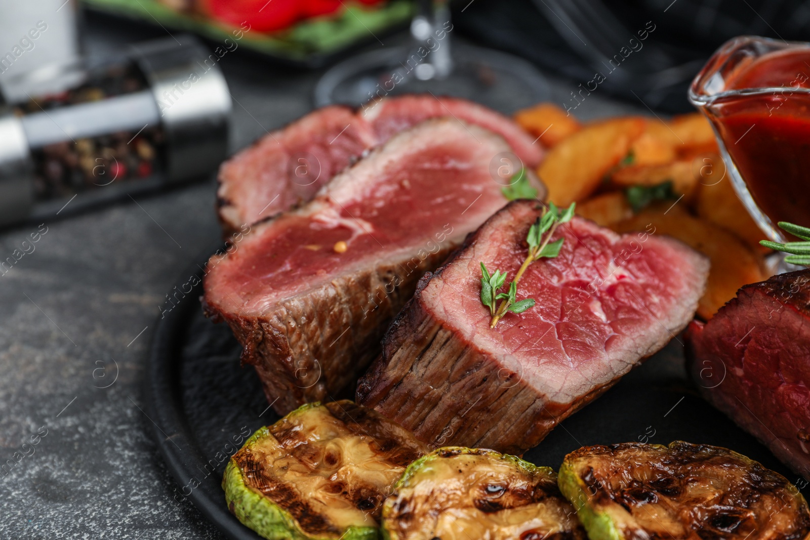 Photo of Delicious sliced beef tenderloin served on grey table, closeup