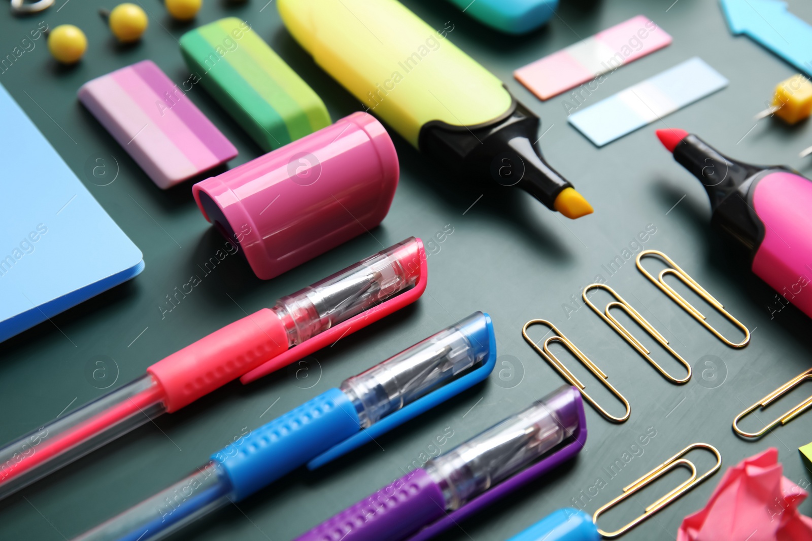 Photo of Different colorful stationery on chalkboard surface. Back to school