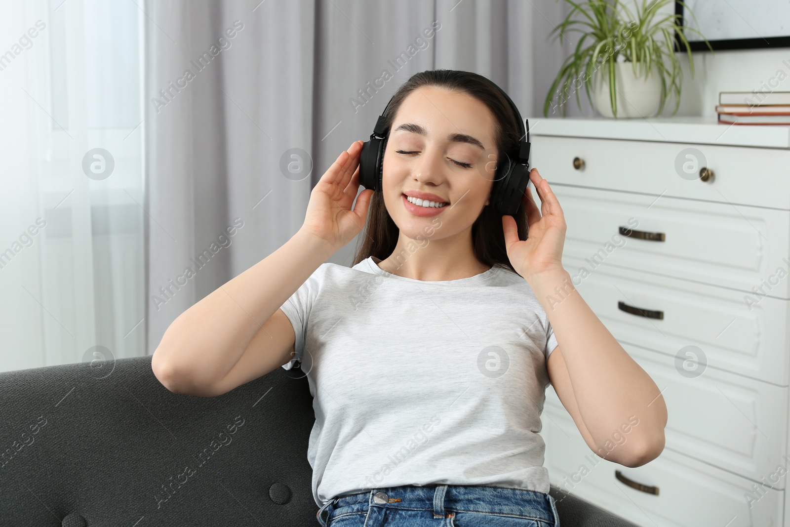 Photo of Happy woman in headphones enjoying music on soft sofa at home