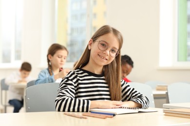 Photo of Portrait of smiling little girl studying in classroom at school