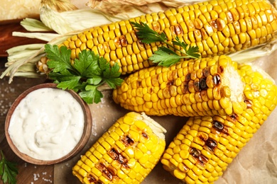 Delicious grilled corn cobs on table, flat lay