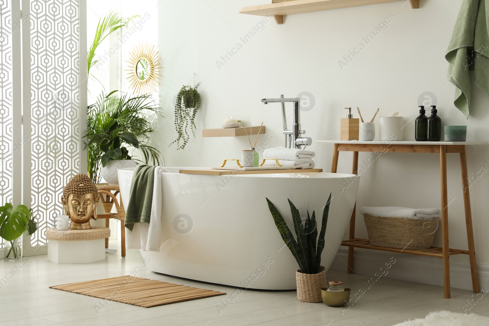 Photo of Stylish bathroom interior with modern tub, houseplants and beautiful decor. Home design