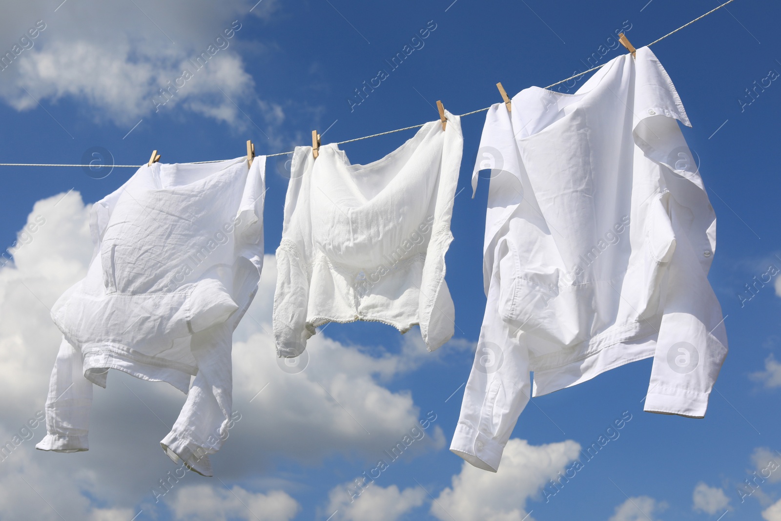 Photo of Clean clothes hanging on washing line against sky. Drying laundry