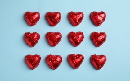 Photo of Heart shaped chocolate candies on light blue background, flat lay. Valentine's day treat
