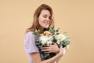 Beautiful woman with bouquet of flowers on beige background