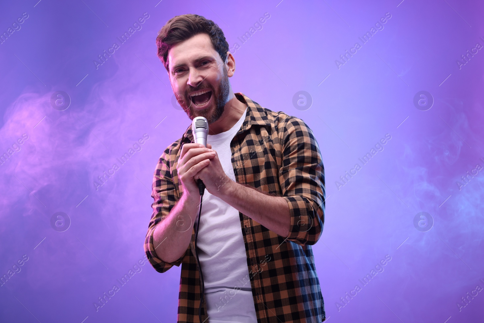 Photo of Handsome man with microphone singing in neon lights