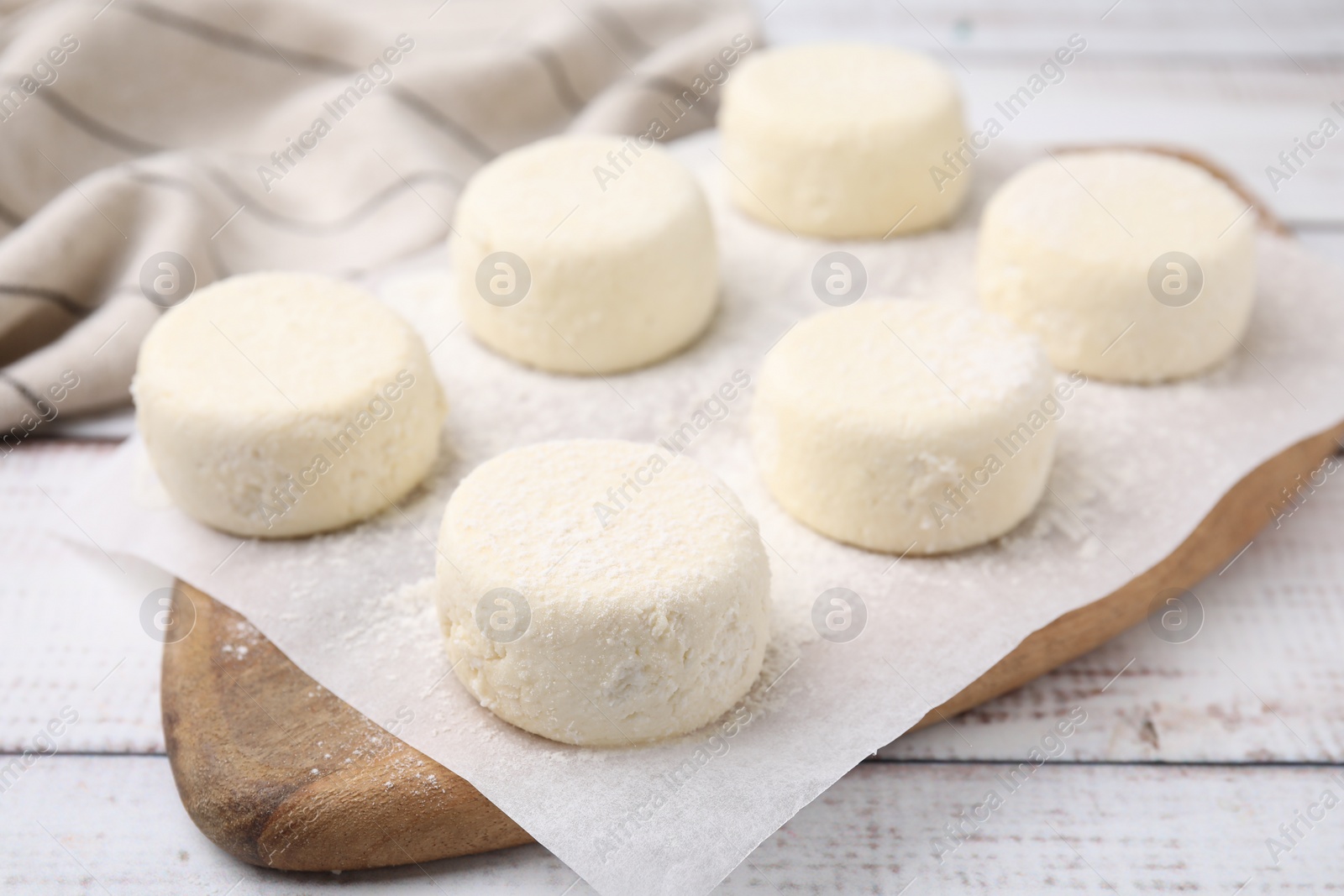 Photo of Uncooked cottage cheese pancakes on white wooden table, closeup