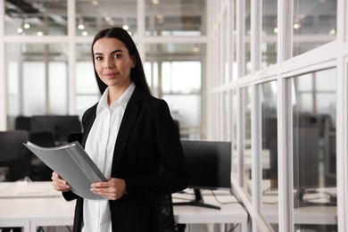 Beautiful woman with folder in office, space for text. Lawyer, businesswoman, accountant or manager