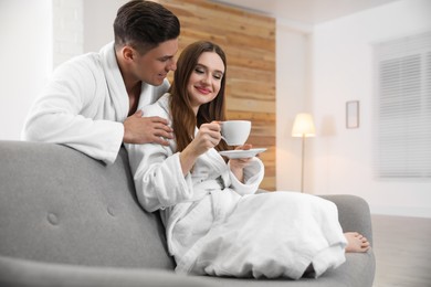 Man in bathrobe hugging his girlfriend with coffee at home